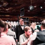Ein professioneller Pokerspieler, der konzentriert an einem Pokertisch sitzt, umgeben von Chips und Karten.