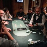 Ein professioneller Pokerspieler sitzt an einem Spieltisch, umgeben von Chips und Spielkarten. Er hat einen konzentrierten Ausdruck und scheint seine nächste Spielstrategie zu planen.