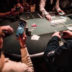 Ein professioneller Pokertisch mit grünem Filz, umgeben von Spielern, die Karten halten und Pokerchips stapeln.