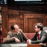 Ein bunter Pokertisch mit Spielkarten, Pokerchips und Getränken, umgeben von einer Gruppe von Menschen, die konzentriert und gesellig miteinander spielen.