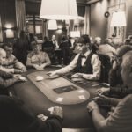 Ein professioneller Pokerspieler, der konzentriert an einem Pokertisch sitzt und Karten in der Hand hält, umgeben von anderen Spielern und Pokerchips.