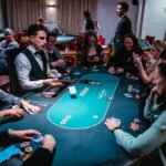 Ein Spieler mit Sonnenbrille und Kappe hält seine Pokerkarten in der Hand und wirft einen intensiven Blick auf den Pokertisch während eines Turniers.
