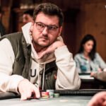 Ein Haufen Pokerchips in verschiedenen Farben und Werten, der auf einem grünen Pokertisch liegt.