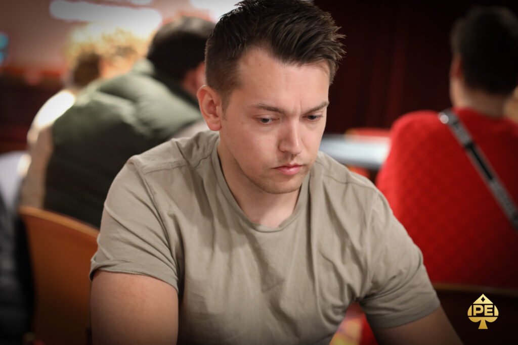 Ein Mann und eine Frau sitzen an einem Pokertisch und halten ihre Karten in der Hand. Sie scheinen konzentriert und ernsthaft in das Spiel vertieft zu sein. Im Hintergrund sind Pokerchips und