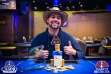 Ein glücklicher Pokerspieler, der jubelt und eine Trophäe in die Luft hält, umringt von anderen Spielern und einem großen Publikum.