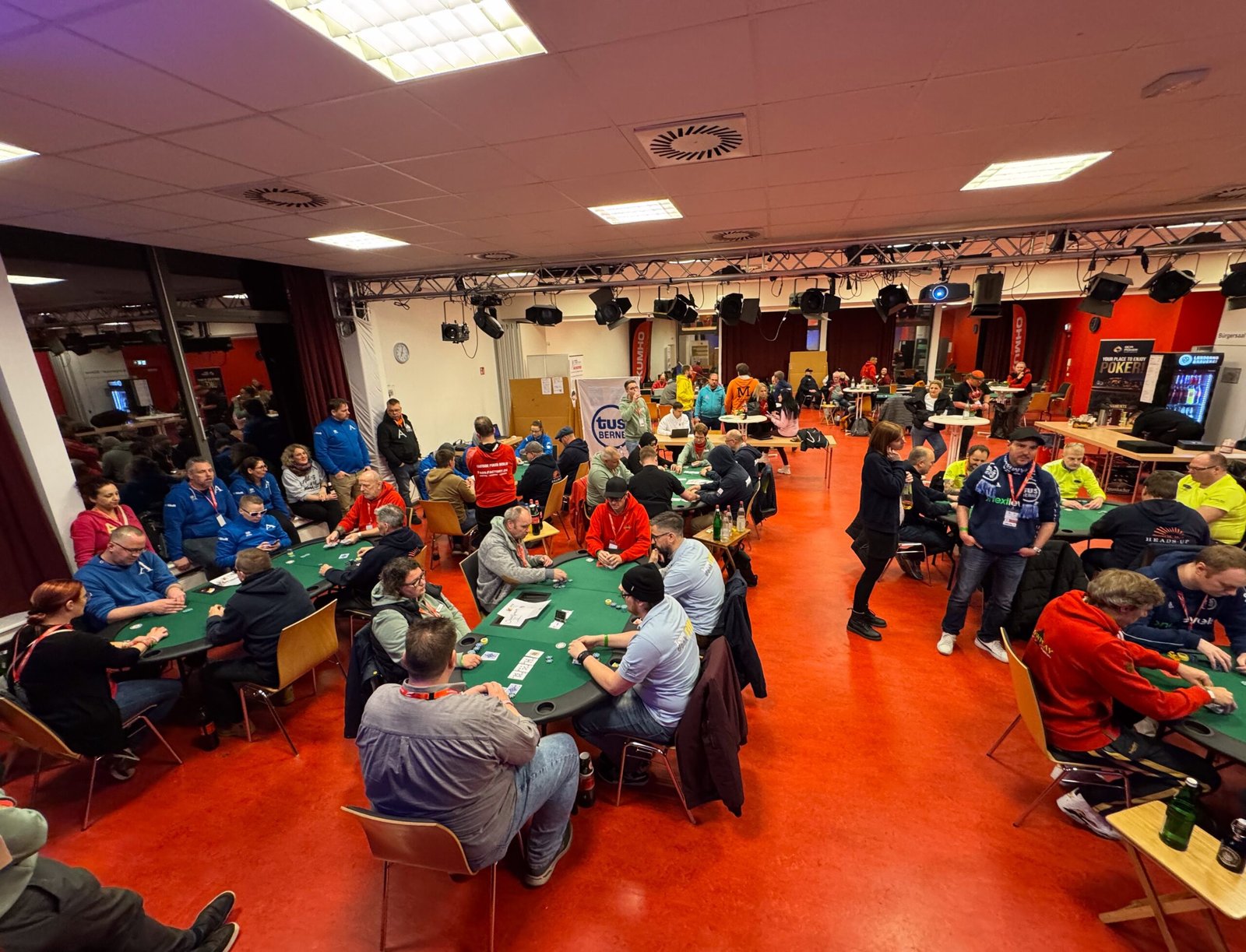 Ein Mann und eine Frau spielen Poker am Tisch in einem Casino. Der Mann hat eine Hand mit Karten vor sich, während die Frau ihre Chips stapelt. Die Atmosphäre ist konzentriert und spannend.