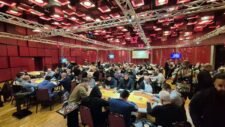 Ein Mann und eine Frau sitzen an einem Pokertisch und betrachten konzentriert ihre Karten. Das Bild zeigt eine spannende Pokerrunde in einem eleganten Raum mit gedämpftem Licht.