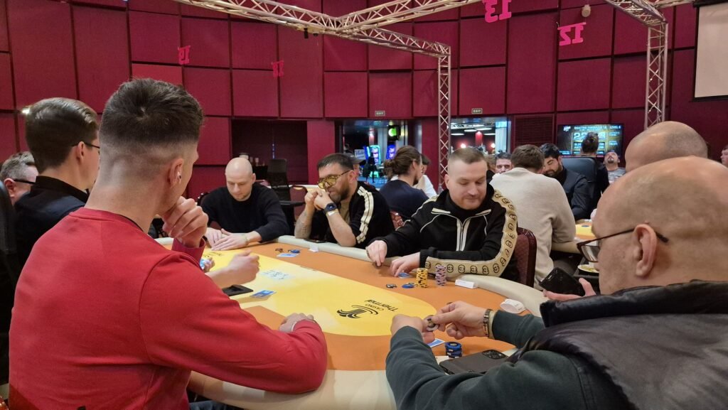 Ein Mann in einem dunklen Anzug und mit einer Sonnenbrille spielt Poker und hält eine Hand mit König-Karten. Er sitzt an einem Pokertisch mit grünem Filz und Chips.