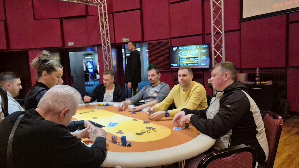 Ein Foto eines Pokertisches mit Spielkarten, Pokerchips und Getränken während eines spannenden Spiels.