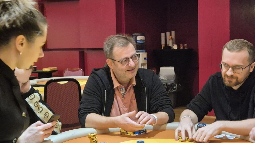 Ein Mann mit einer Pokerkarte in der Hand, der auf einen Tisch schaut.