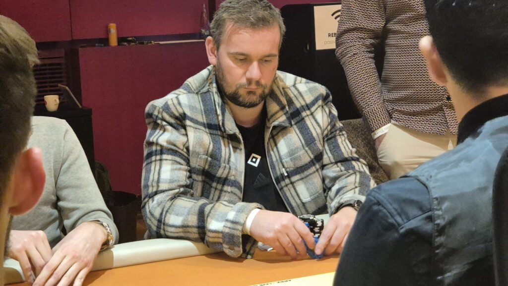 Ein professioneller Pokertisch mit grünem Filz, umgeben von Spielkarten, Jetons und einem Dealer-Button.