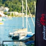 Ein professioneller Pokertisch mit grünen Filz, umgeben von Spielkarten, Pokerchips und einem Dealer-Button. Spieler sitzen an dem Tisch und konzentrieren sich auf ihre Karten.