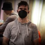 Ein Mann und eine Frau sitzen an einem Pokertisch und spielen Karten. Der Mann hat eine Hand mit Chips vor sich und schaut konzentriert auf seine Karten, während die Frau lächelnd ihre Karten betracht
