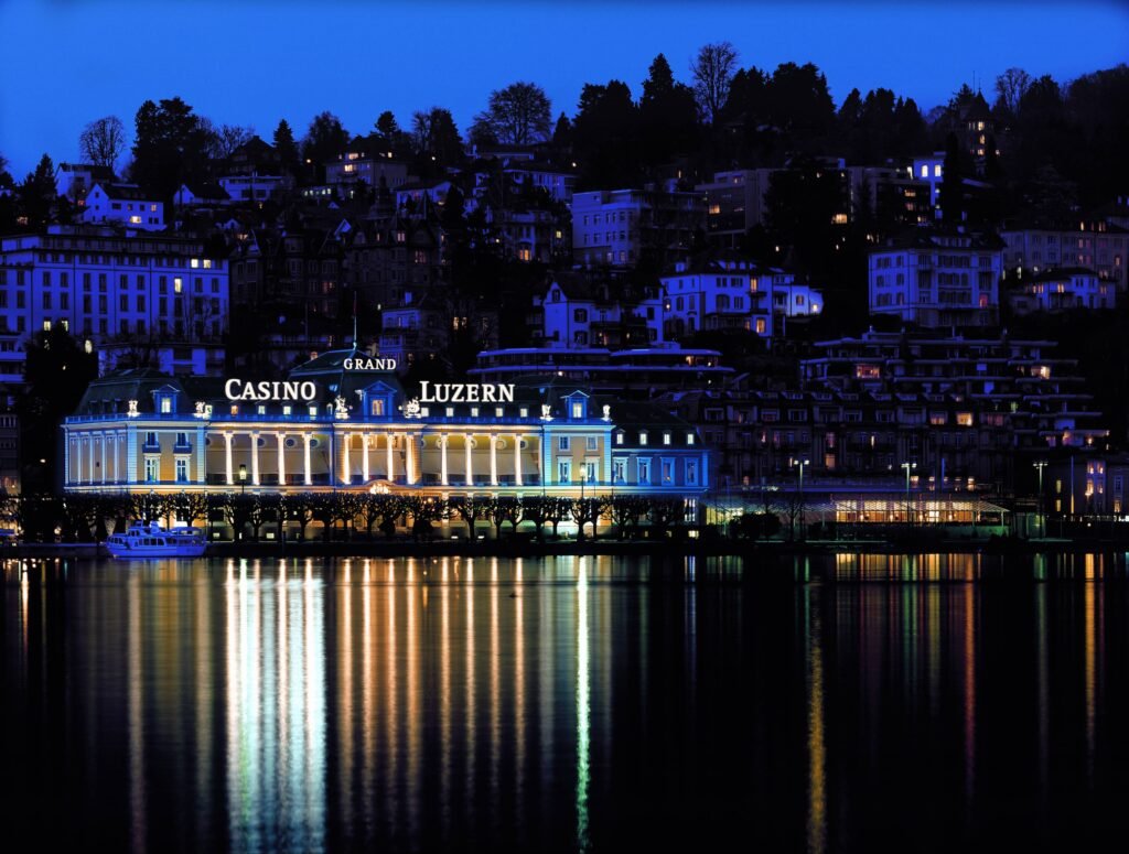 Ein eleganter Spieltisch im Grand Casino Luzern mit grüner Filzoberfläche, umgeben von Stühlen und einer glamourösen Beleuchtung.