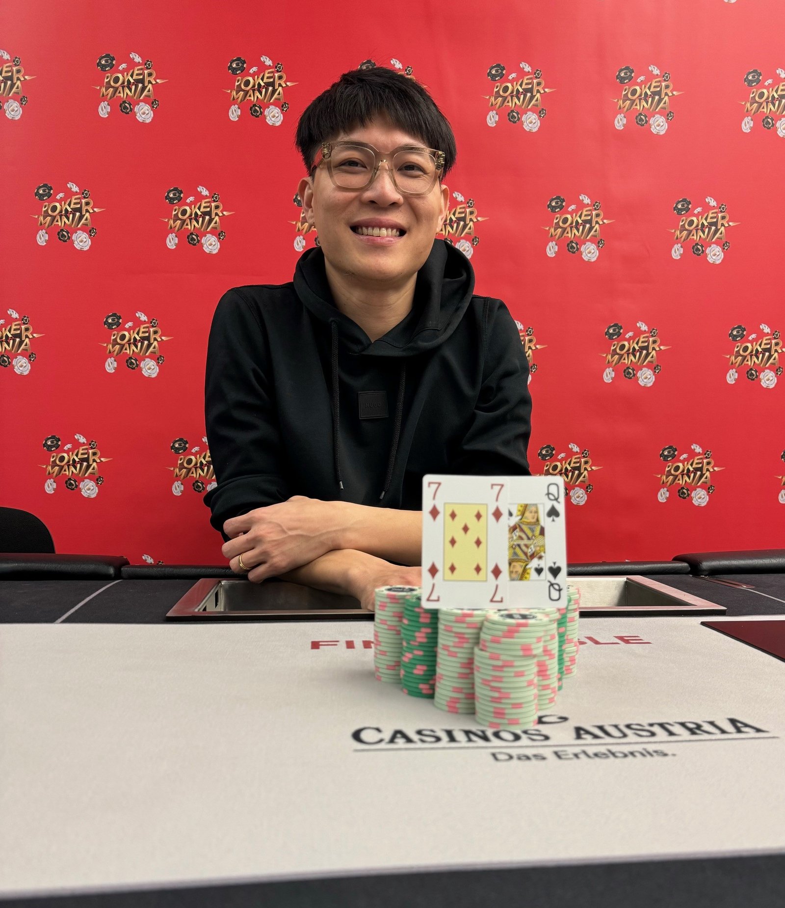 Ein Bild von einer Pokerrunde in einem Casino mit fünf Personen um einen Tisch herum sitzend, Karten haltend und Pokerchips stapelnd. Die Spieler sind konzentriert und gespannt.