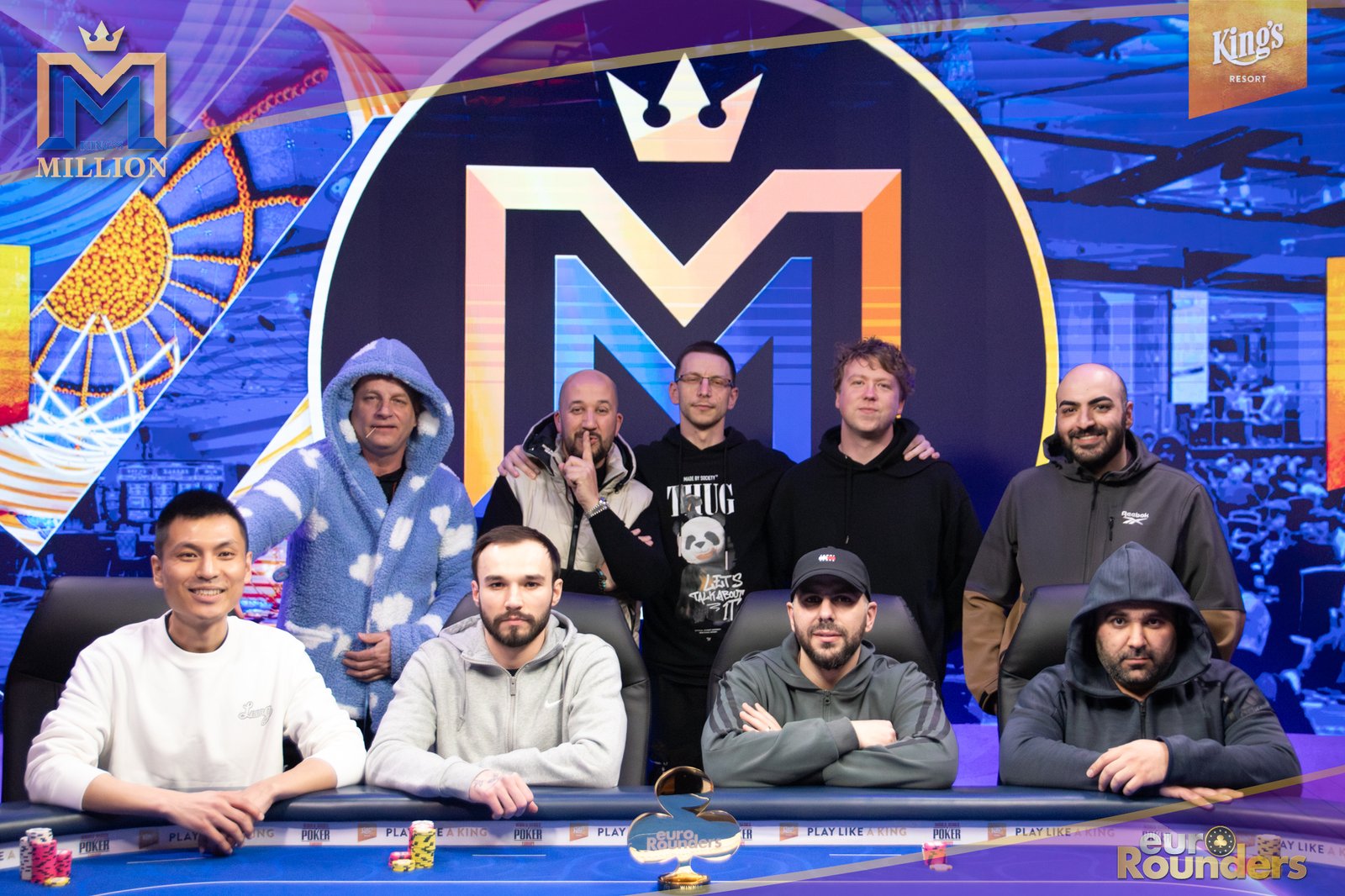 Ein Mann sitzt an einem Pokertisch mit Chips und Karten. Er hält eine Hand mit Ass und König. Im Hintergrund sind weitere Spieler und eine Dealerin zu sehen.