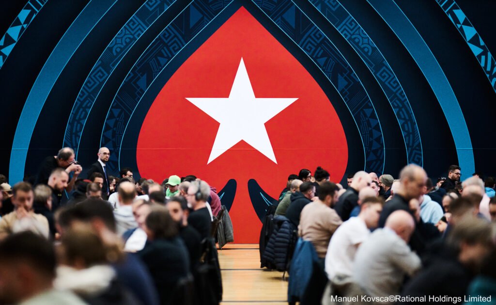 Ein bunter Haufen von Pokerchips in verschiedenen Farben und Werten, die auf einem Tisch gestapelt sind. Einige Chips sind lose verstreut und funkeln im Licht. Ein Dealer-Button liegt in der Mitte