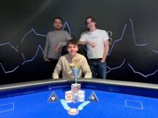 Ein Mann und eine Frau sitzen an einem Pokertisch, konzentriert auf ihre Karten und Chips. Die Frau trägt eine schwarze Bluse und der Mann ein blaues Hemd. Im Hintergrund sind Pokerchips