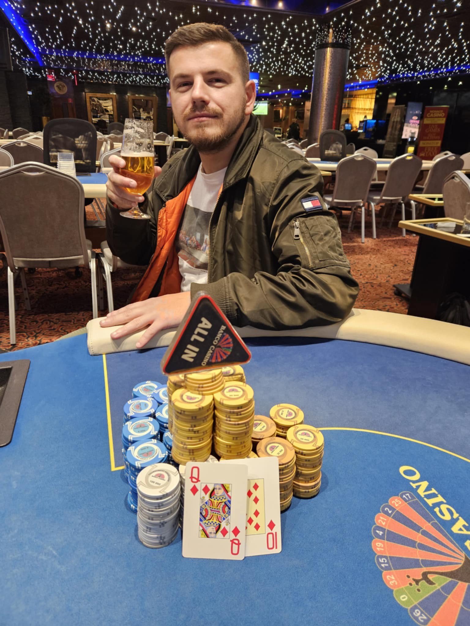 Ein professioneller Pokerspieler mit Sonnenbrille und einem Stapel von Pokerchips vor sich, der konzentriert auf seine Karten schaut.