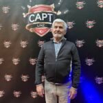Ein professioneller Pokertisch mit grünem Filz und einer Reihe von Pokerchips, Karten und Getränken darauf, bereit für eine Pokerrunde.