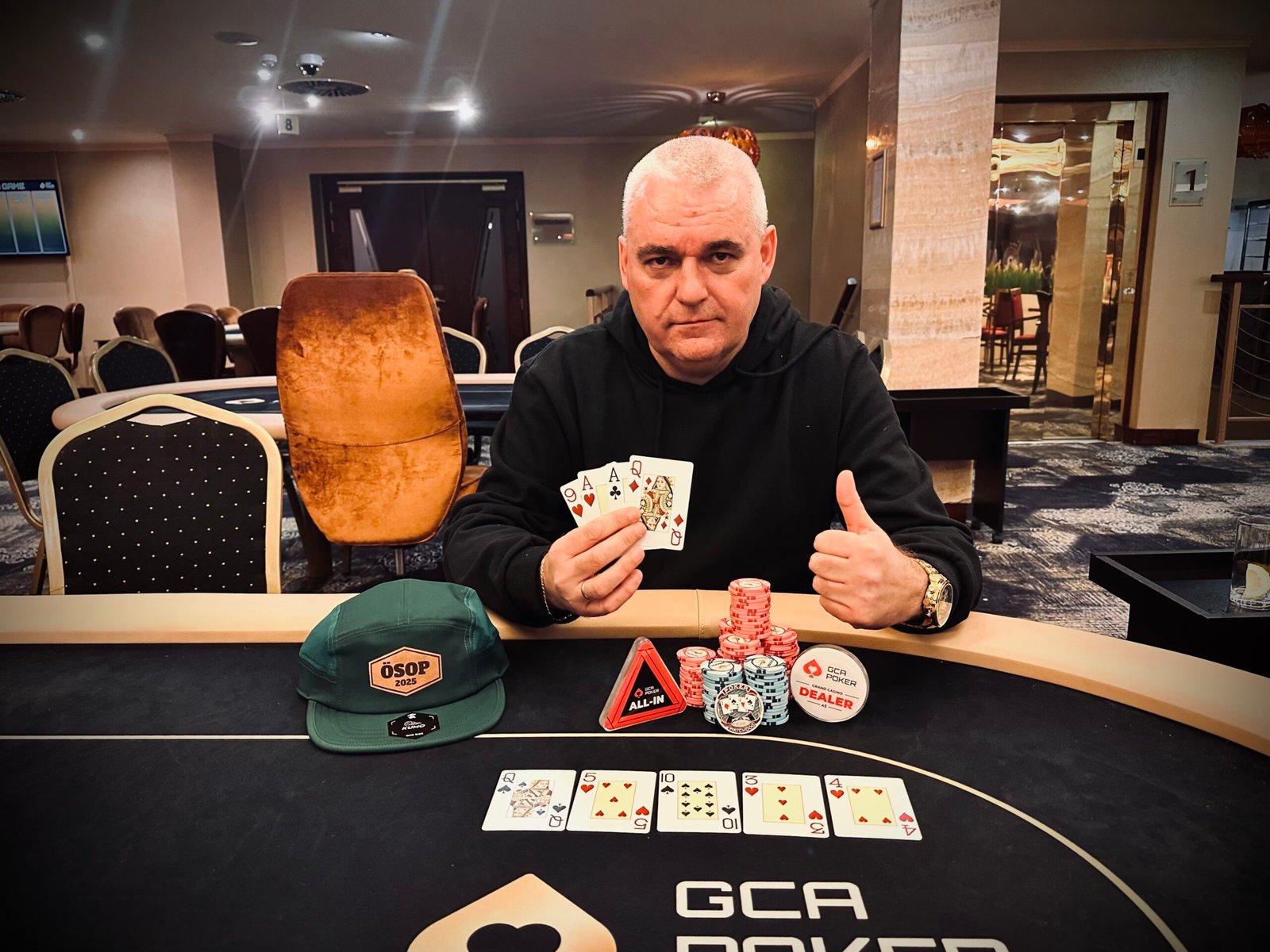 Ein Gruppenbild von fünf Personen, die um einen Pokertisch sitzen und Karten halten. Sie lächeln und scheinen eine entspannte Atmosphäre zu genießen.