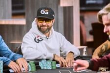 Ein Mann sitzt an einem Pokertisch und betrachtet konzentriert seine Karten. Im Hintergrund sind andere Spieler und Dealer zu sehen. Das Bild zeigt Daniel Negreanu beim Spielen in einem Mixed-Game-T