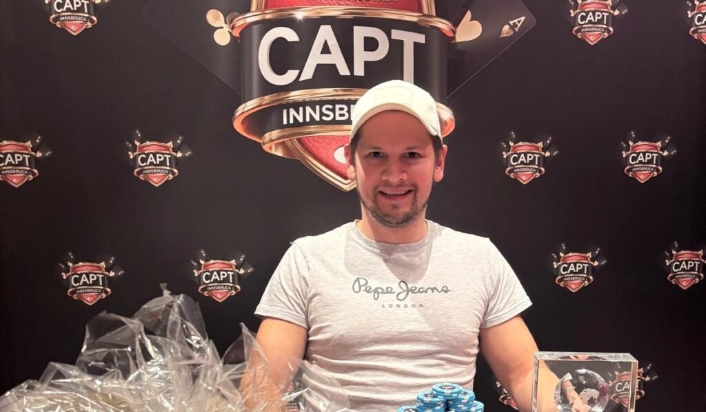 Ein Mann in einem eleganten Anzug hält stolz einen Pokal in die Luft, umgeben von jubelnden Menschen.