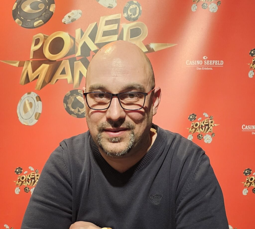 Ein professioneller Pokertisch mit grünem Filz, umgeben von Spielkarten, Jetons und einem Glücksbringer in Form eines vierblättrigen Kleeblatts.