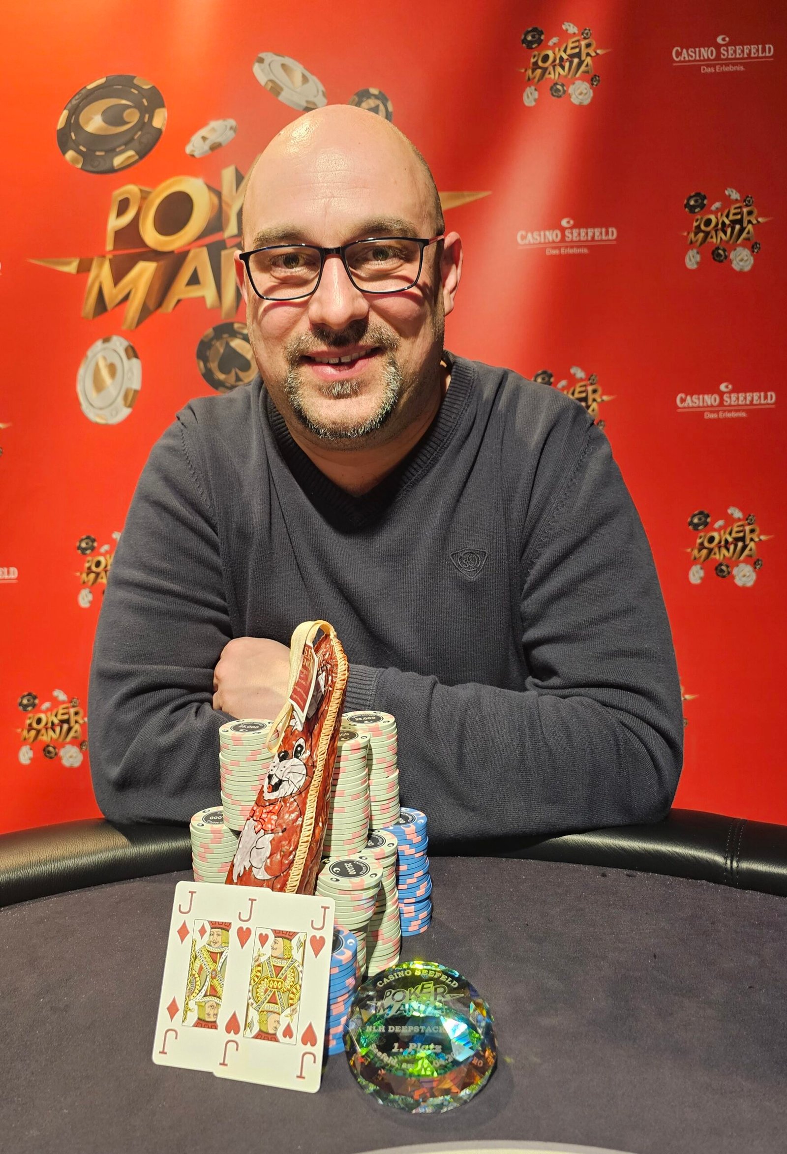 Ein Mann in einem dunklen Anzug spielt Poker an einem eleganten Tisch in einem stilvollen Casino. Er hält seine Karten geheim, während er konzentriert auf seine Gegner blickt. Die Atmosph