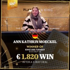 Ein Mann in einem schwarzen Anzug hält zwei Spielkarten in der Hand und schaut konzentriert auf den Pokertisch. Im Hintergrund sind andere Spieler und Pokerchips zu sehen.