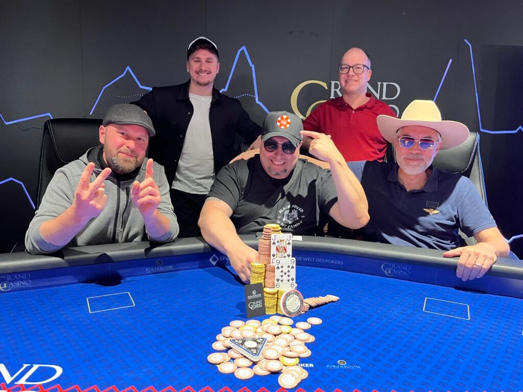 Ein Mann und eine Frau sitzen an einem Pokertisch und spielen ein intensives Spiel. Der Mann hat eine Hand mit Karten in der Luft, während die Frau konzentriert ihre Karten betrachtet. Im Hintergrund sind