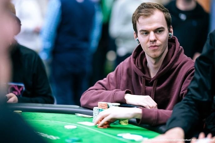 Ein Mann namens Michel Molenaar, der an einem Pokertisch sitzt und Karten hält, während er konzentriert in die Kamera schaut.