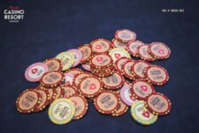 Ein Mann sitzt an einem Pokertisch und hält zwei Spielkarten in der Hand, während er konzentriert auf seine Gegner schaut. Die Spannung des Pokerspiels ist spürbar.