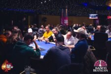 Ein Foto, das während des ersten Tages eines Pokerturniers aufgenommen wurde. Spieler sitzen an einem Tisch und halten Karten in der Hand. Die Spannung des Wettbewerbs ist spürbar.