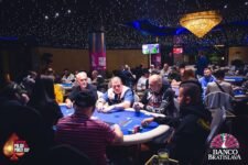 Ein Pokertisch mit Spielkarten, Pokerchips und Spielern, die ihre Karten prüfen und Wetten platzieren während eines Pokerturniers.