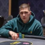 Ein professioneller Pokertisch mit grünem Filz, umgeben von Spielern, die Karten halten und Pokerchips stapeln.