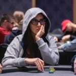 Ein Mann und eine Frau sitzen an einem Pokertisch und spielen Karten. Der Mann hält Karten in der Hand, während die Frau konzentriert auf ihre Karten schaut. Im Hintergrund sind Pokerchips und