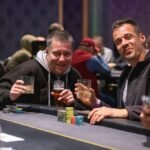 Ein Stapel von Pokerchips in verschiedenen Farben und Werten, der auf einem grünen Pokertisch liegt.