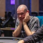 Ein Mann und eine Frau spielen Poker an einem eleganten Tisch in einem Casino, umgeben von Pokerchips und Karten.