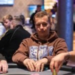 Ein Mann und eine Frau sitzen an einem Pokertisch und spielen Texas Hold'em. Der Mann hat eine Hand voller Pokerchips und schaut konzentriert auf seine Karten, während die Frau mit einem selbstbewussten Blick