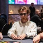 Ein professioneller Pokertisch mit Chips und Karten, auf dem Spieler ihre Hände halten und konzentriert spielen.