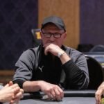 Ein Mann und eine Frau sitzen an einem Pokertisch und spielen Karten. Der Mann hat eine Hand mit Chips vor sich liegen, während die Frau konzentriert ihre Karten betrachtet. Im Hintergrund sind Glück