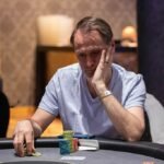 Ein Mann und eine Frau sitzen an einem Pokertisch, konzentriert auf ihre Karten und Chips. Der Mann hat eine starke Pokerhand und lächelt selbstbewusst, während die Frau nachdenklich ihre Option