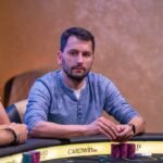 Ein professioneller Pokertisch in einem eleganten Raum mit grünen Filz und einem Stapel Pokerchips.