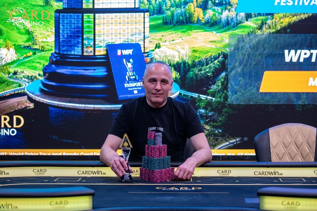 Ein Mann sitzt an einem Pokertisch und hält Karten in der Hand, während er konzentriert auf seine Gegner schaut.