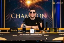 Ein Mann in einem schwarzen Anzug und einer Sonnenbrille, Jesse Lonis, steht jubelnd vor einem Pokertisch. Er hält eine Trophäe in die Luft, umgeben von Menschen, die ihn fei