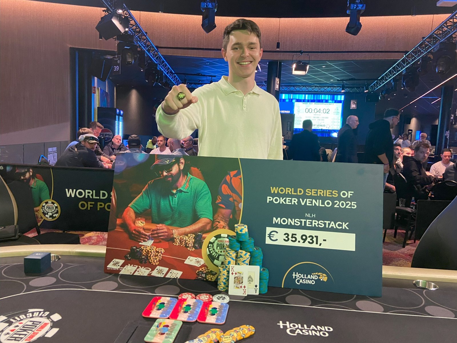 Ein Poker-Tisch mit zahlreichen stapelbaren Chips in verschiedenen Farben und Werten darauf. Ein Spieler setzt gerade einen großen Stapel Chips in die Mitte des Tisches.