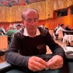 Ein Mann und eine Frau spielen Poker an einem Tisch in einem eleganten Casino. Der Mann hat eine Hand mit Karten in der Luft, während die Frau konzentriert ihre Karten betrachtet. Die Szene ist durch elegante