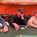 Ein lebendiger Pokertisch mit Spielkarten, Chips und Getränken, umgeben von konzentrierten Spielern in einem eleganten Raum mit gedämpftem Licht.