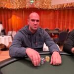 Ein Mann und eine Frau sitzen an einem Pokertisch und schauen konzentriert auf ihre Karten. Um sie herum stehen Chips und Getränke.